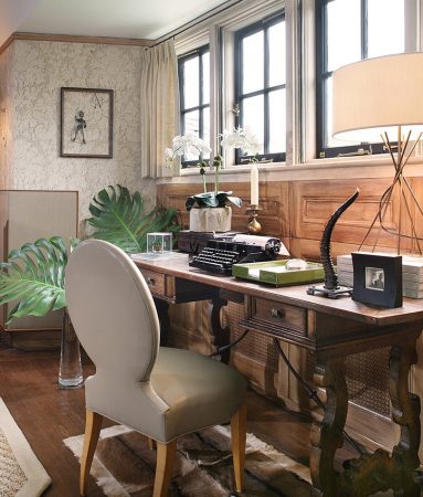 An eclectic home office featuring a desk, chair, and lamp.