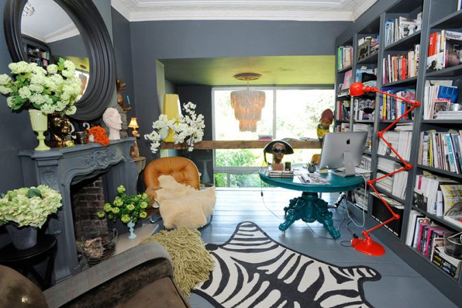 An eclectic home office with a zebra print rug in a room with a fireplace.