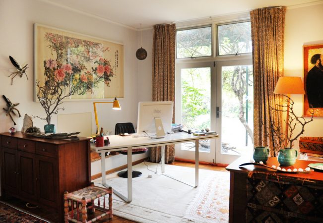 An eclectic home office with a desk, chair, and window.