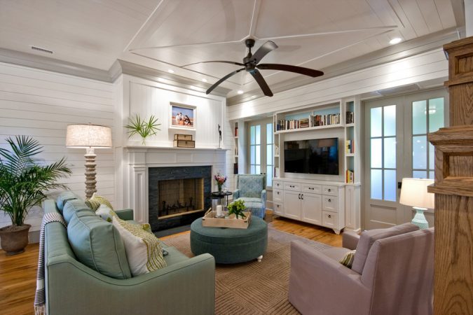 A family room with a fireplace and ceiling fan.