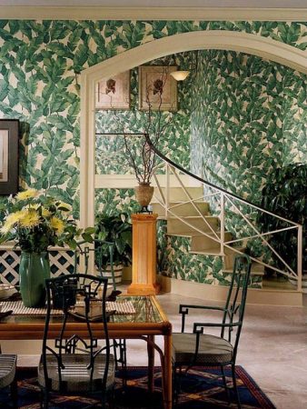 A dining room with tropical green wallpaper.