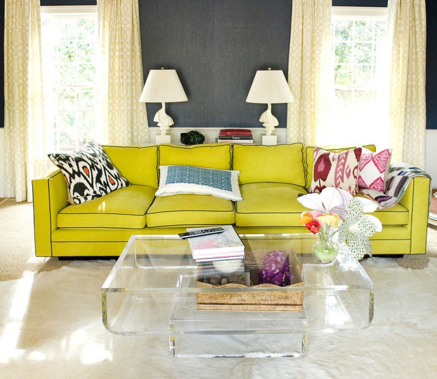 A living room with a yellow couch and a glass coffee table.