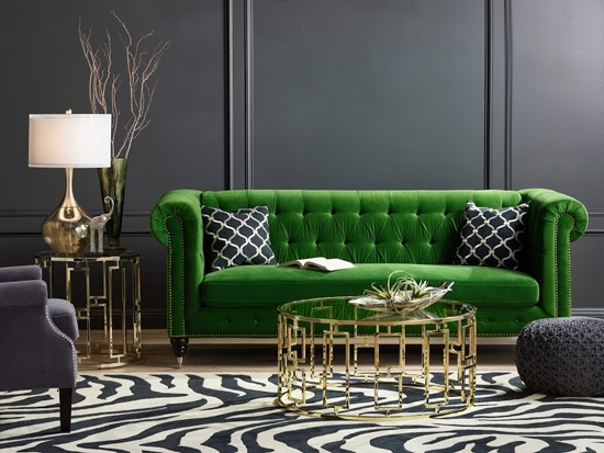A living room with a statement green velvet sofa and zebra print rug.