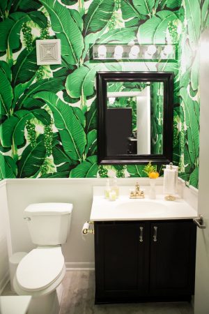 A tropical bathroom with a green and white wallpaper.