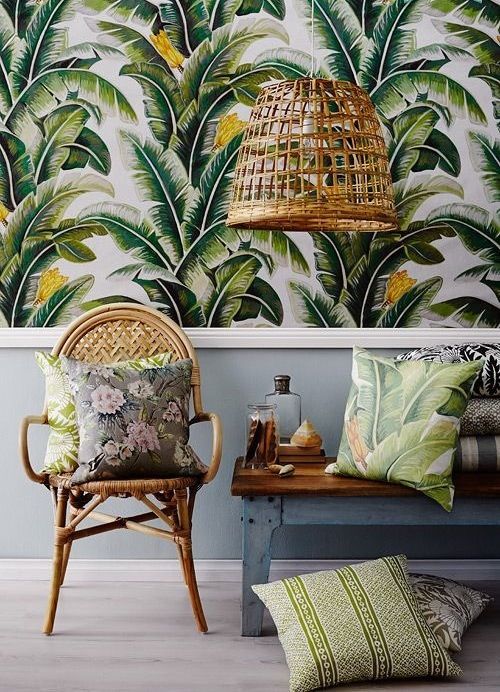A room with tropical wallpaper and a wicker chair.