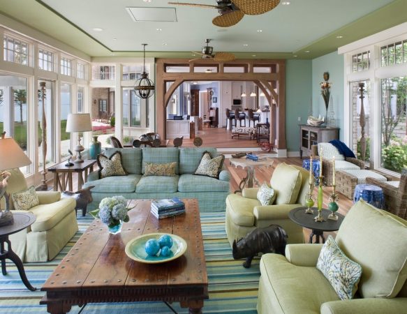 A bright living room with blue and green furniture and a ceiling fan.