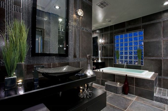 A stunning bathroom with elegant black tile and a luxurious black tub.