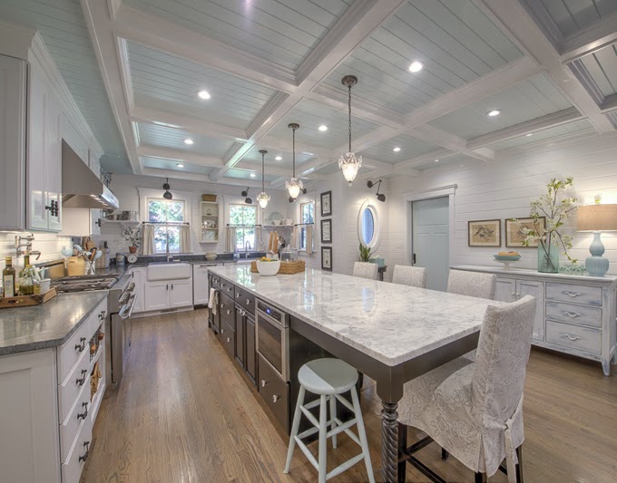 A Cape Cod kitchen with a large island and white cabinets.