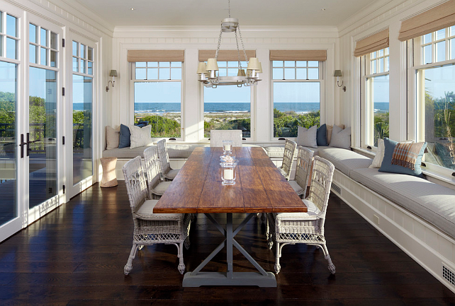 A Cape Cod dining room with large windows overlooking the ocean.