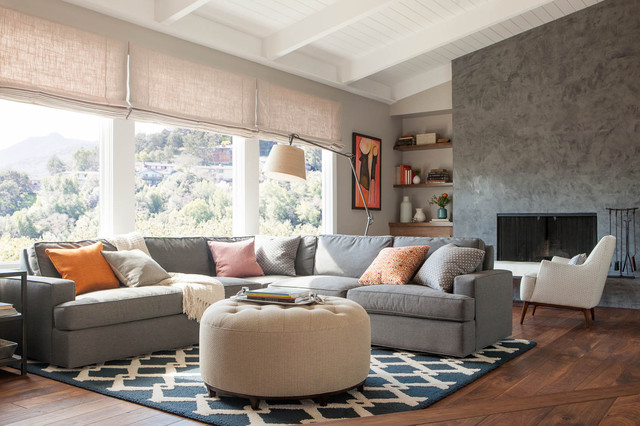 A living room with a grey couch and ottoman, featuring cream accents.