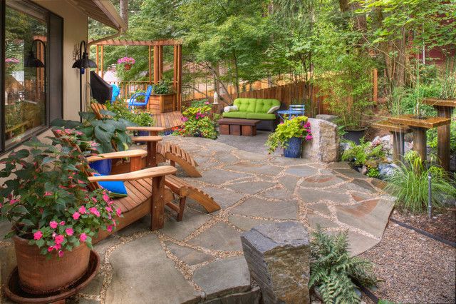 A stone patio with wooden furniture.