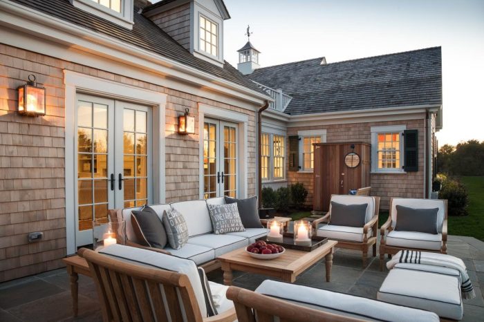 An outdoor living area with white furniture and a fireplace inspired by Cape Cod.