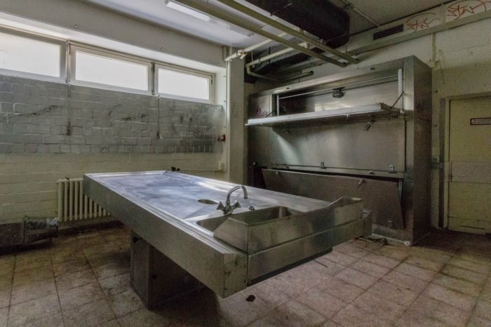 An abandoned room in Germany with a metal table and a sink.