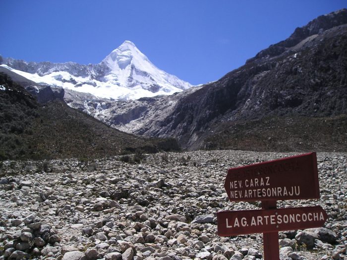 A sign in the middle of a rocky area with a mountain in the background in Peru.