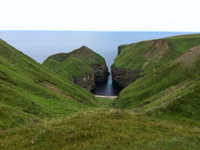 Two cliffs in the middle of a grassy hill in Scotland.