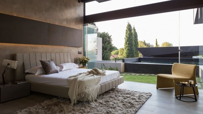 A modern bedroom with a glass wall and a bed at Kloff Road House.