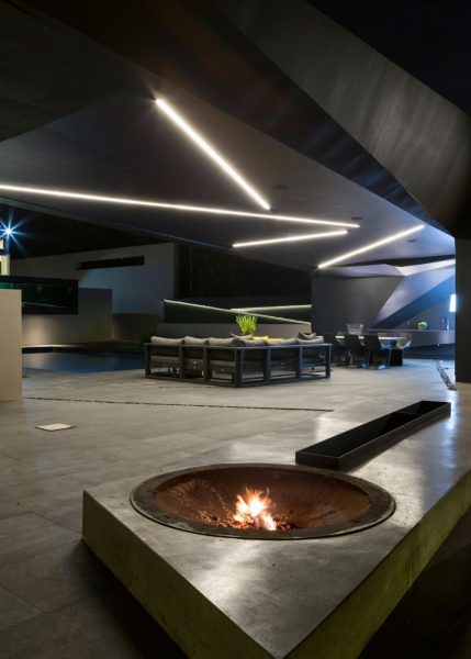 A fire pit in the middle of a modern house at night, located on Kloff Road.