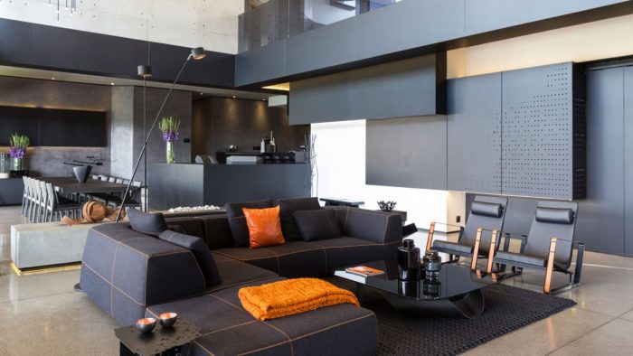 A modern living room with black furniture and orange accents at Kloff Road House.