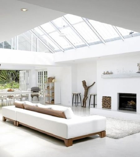 A white living room illuminated by a skylight.