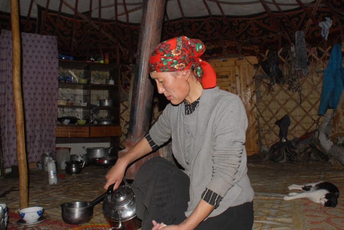 Mongolian woman in a ger, holding a kettle