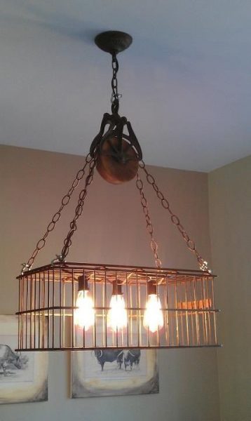 An upcycled chandelier with three lights hanging from it.