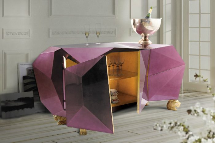A pink and gold faceted-sideboard with a bottle of wine.