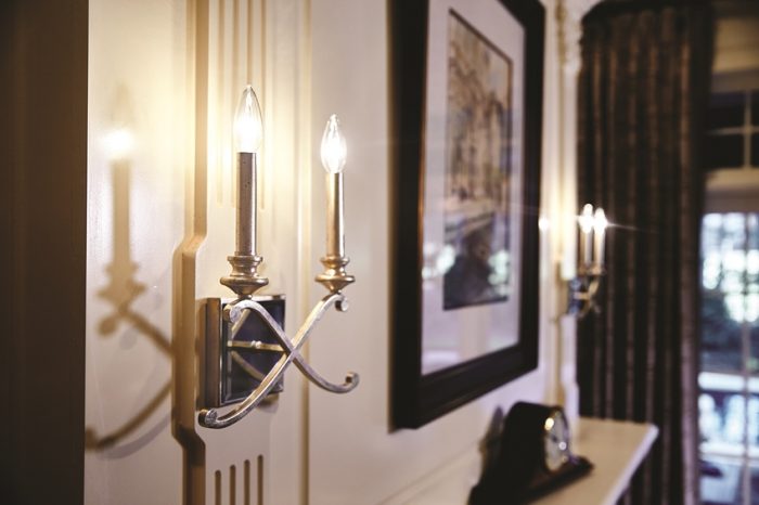 Two sconces on a wall providing lighting next to a picture.