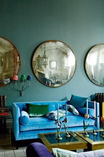 A living room with blue couches and mirrors on the wall.