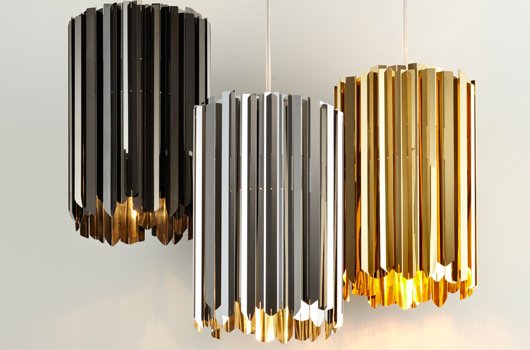 Three faceted black and gold pendant lights hanging from a white wall.