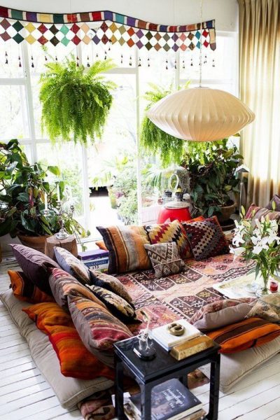 A cozy living room with lots of pillows and plants.