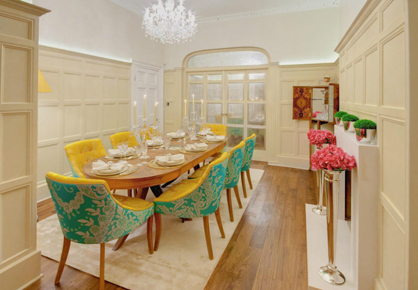 A dining room with bright yellow chairs and a chandelier.