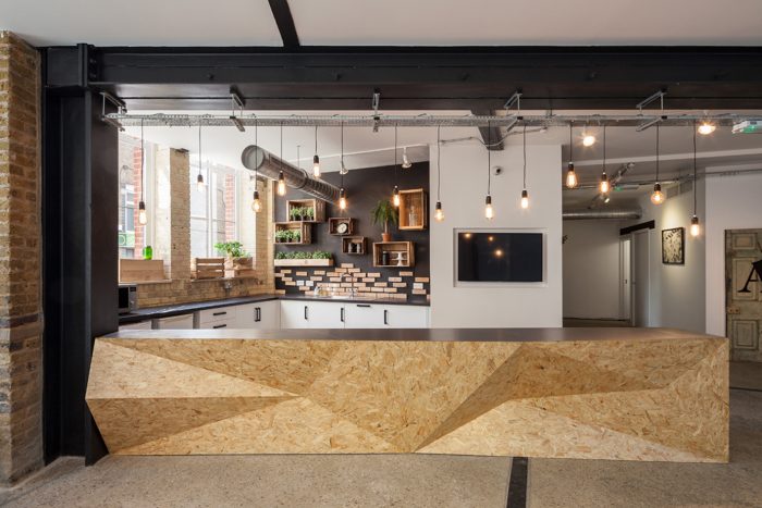 A reception area in a modern office with a faceted wooden counter.