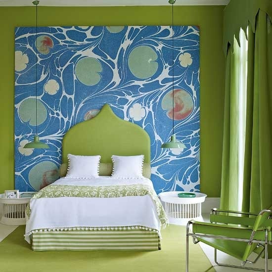 A green and white bedroom with a vibrant mural on the wall.