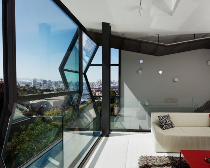 A faceted living room with large windows overlooking a city.