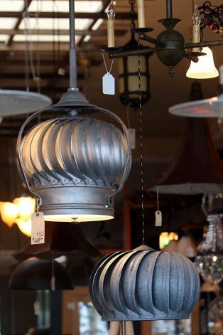 A collection of upcycled metal lamps hanging in a store.