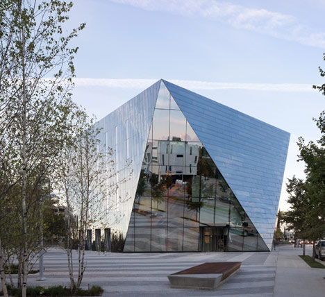 A glass building with a faceted triangular shape.