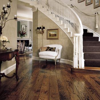 A hardwood flooring entryway with a staircase.