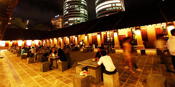 People are sitting at tables in a courtyard in Srilanka at night.