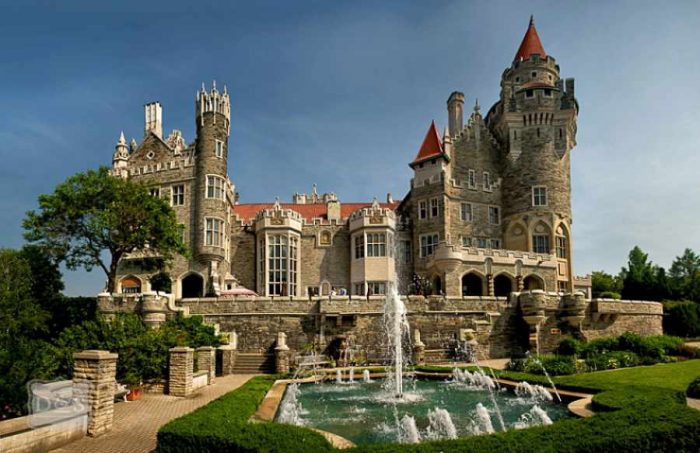 An ornate castle with a fountain in front of it, located in Toronto.
