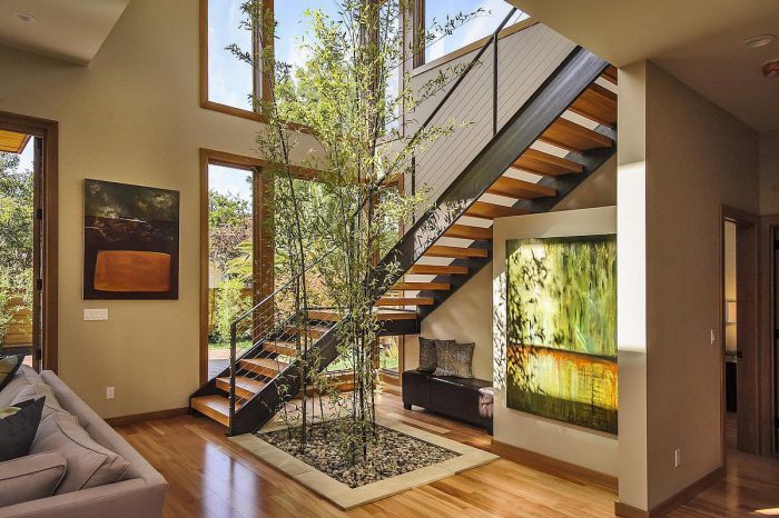A modern home with a living room featuring a staircase and a tree.
