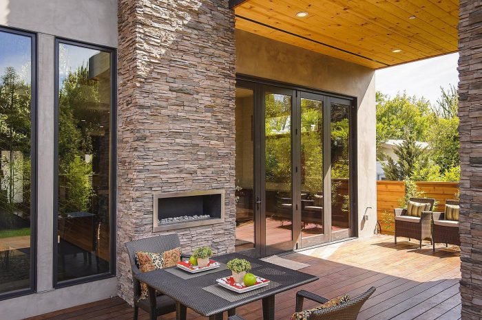 A modern patio with a stone fireplace and patio furniture in a prefabricated modern home.