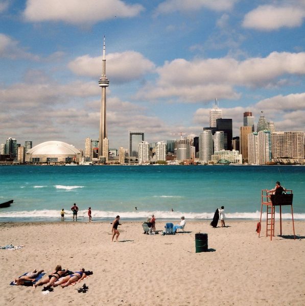 A beach with people on it and the CN Tower in Toronto in the background.