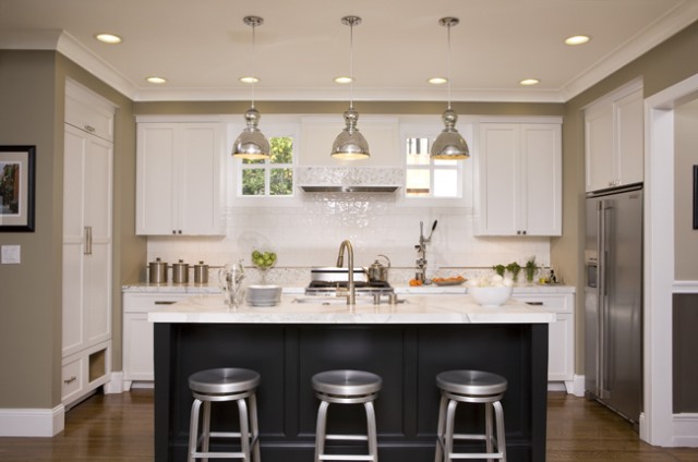 A white kitchen with black counter tops and khaki stools.