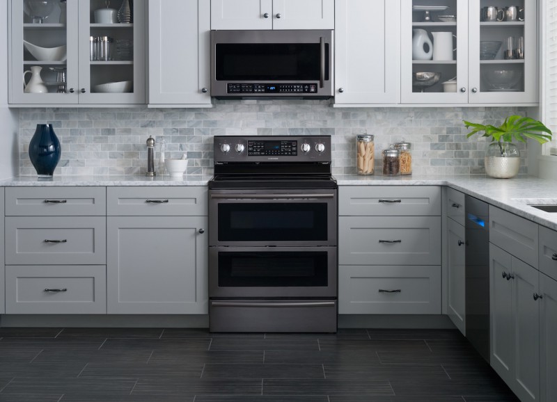 A modern kitchen remodel with gray cabinets and black appliances.