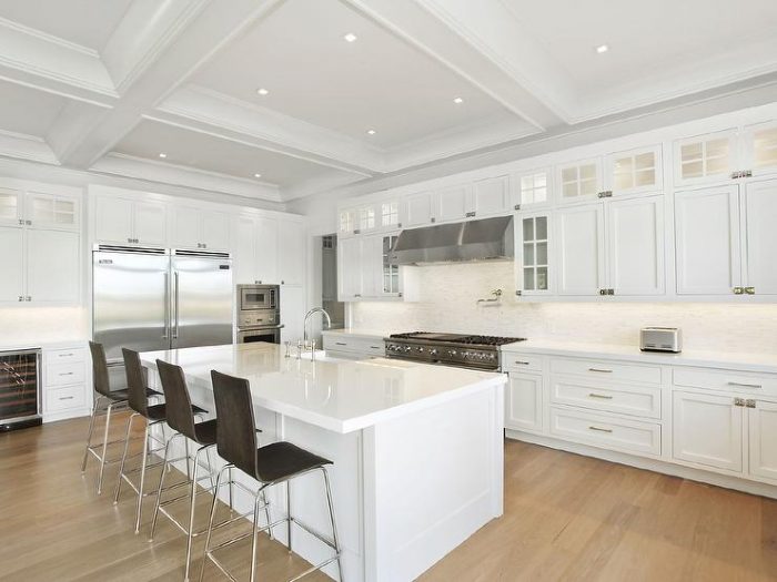 A white kitchen with a center island and bar stools, perfect for a kitchen remodel.