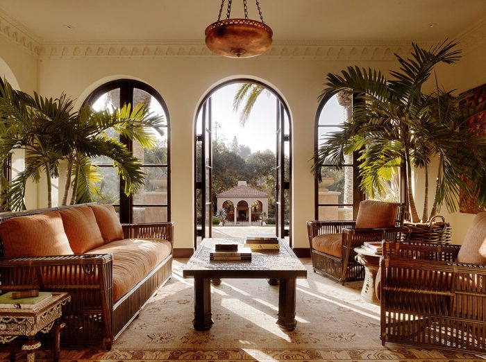 A Mediterranean-style living room with arched windows and wicker furniture.