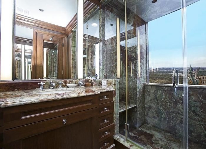 A bathroom with a glass shower stall and marble countertop.