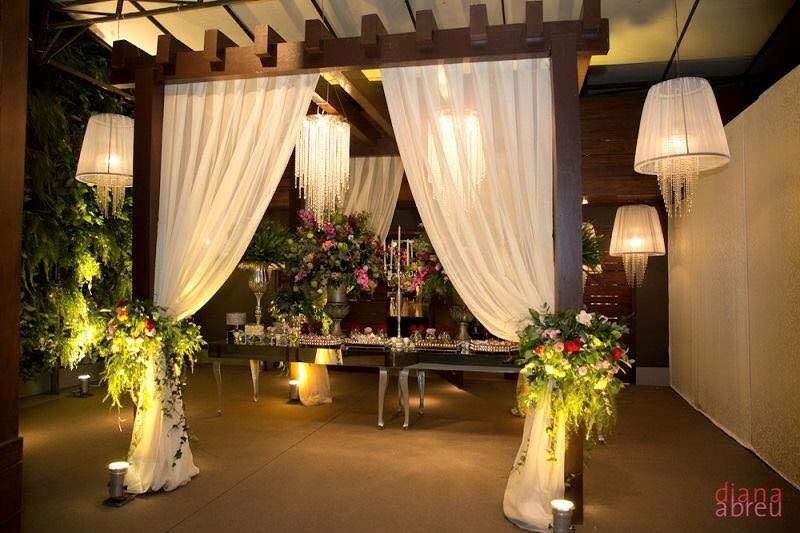 A wedding reception set up with white drapes and lights, featuring a fireplace.