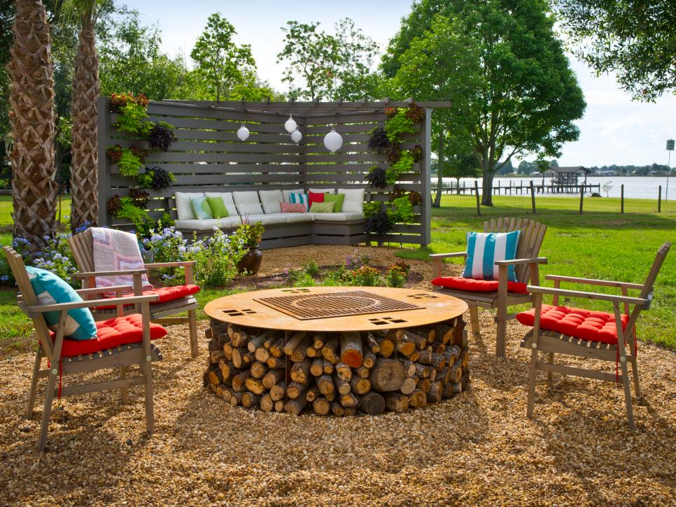 A fireplace pit in a yard with chairs around it.