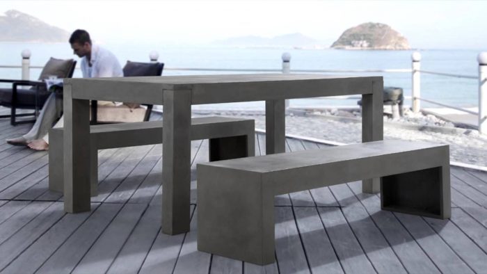 An outdoor DIY concrete table and bench with a view of the ocean.